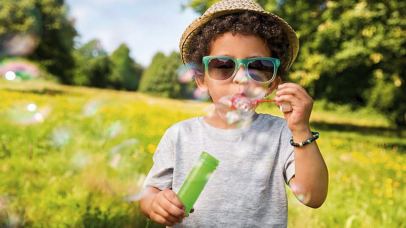 Kind macht Seifenblasen in der Wiese