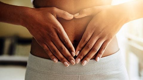 Frau legt ihre Haende auf den Bauch