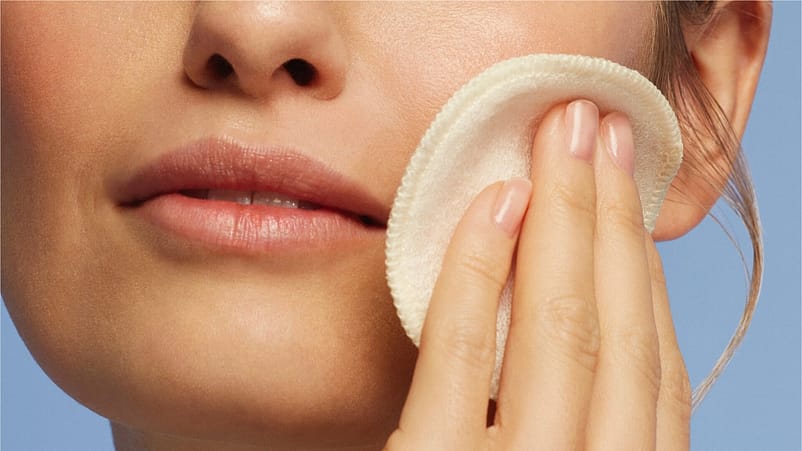 frau rinigt ihr gesicht mit einem Wattepad