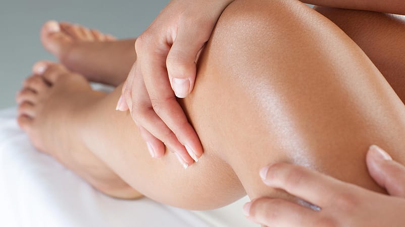 Frau streicht mit der Hand über die Beine