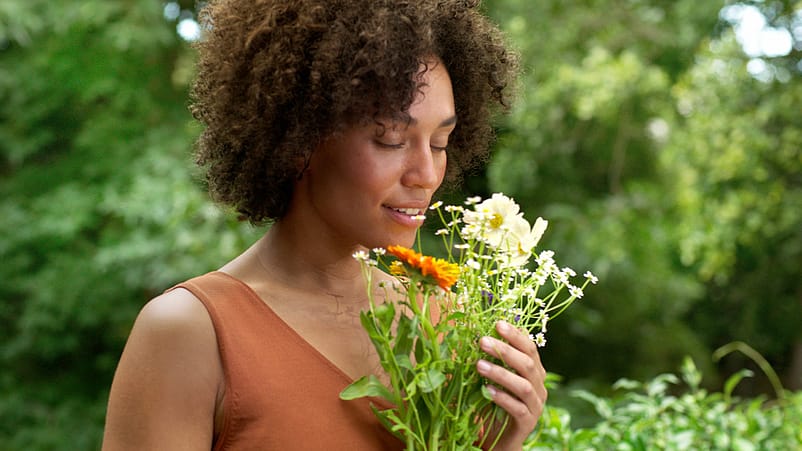 Femme dans la nature sentant les fleurs