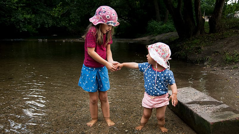 Dos niñas de la mano jugando en el agua