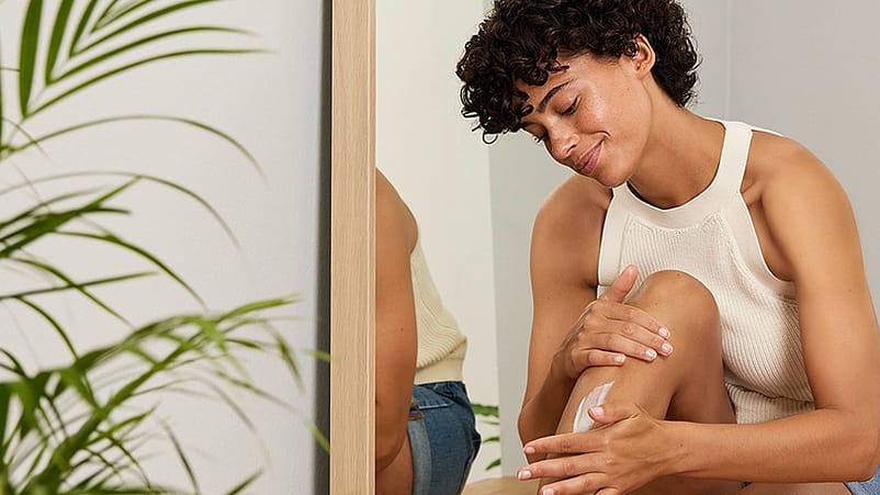 mujer echandose crema en las piernas