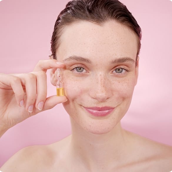 Junge Frau hält sich das Weleda Wildrose Skin Repair Serum an die Wange