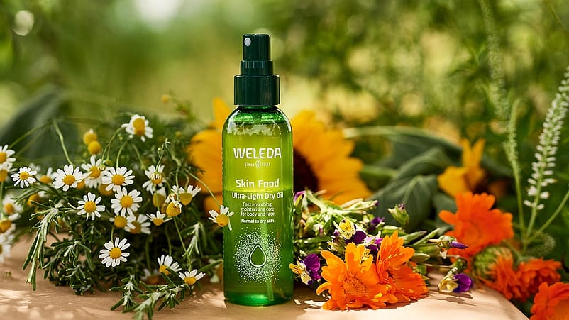 Skin Food Ultra-Light Dry Oil entourée de fleurs