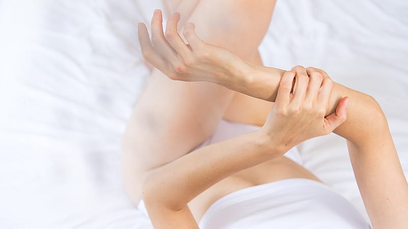 une femme s'applique de l'huile sur les bras