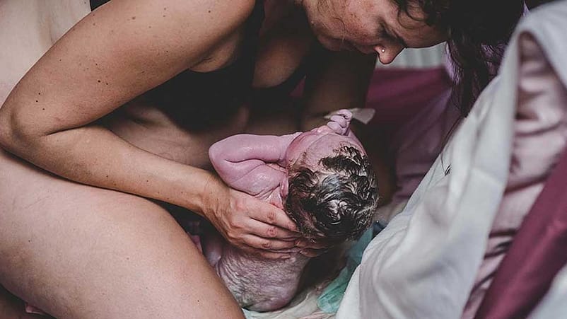 Donna accoglie il bambino alla nascita.