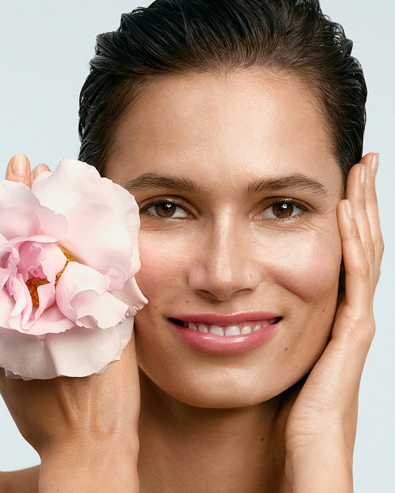 Gesicht einer Frau mit der Blüte einer Wildrose an ihrem Gesicht