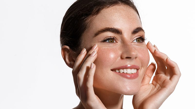 Lächelnde Frau mit Fingerspitzen im Gesicht