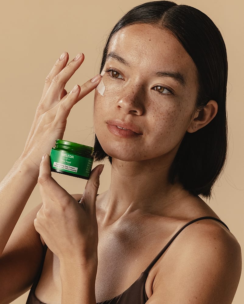 woman applying day cream to cheek