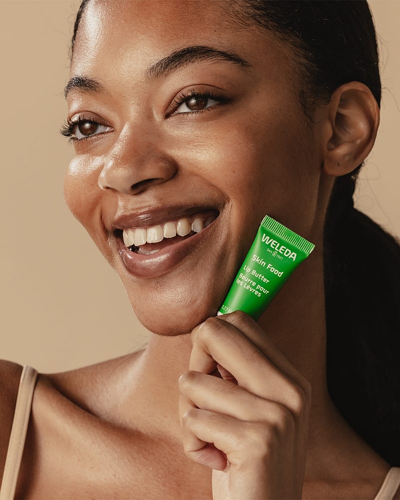 smiling woman holding lip butter tube