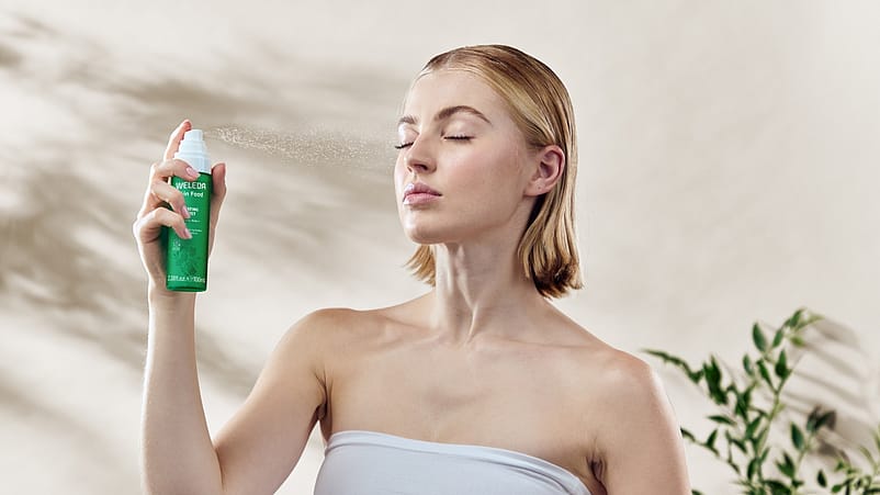 Woman spritzing face with mist