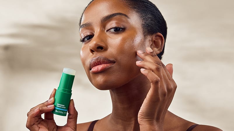 Woman applying serum stick to cheek