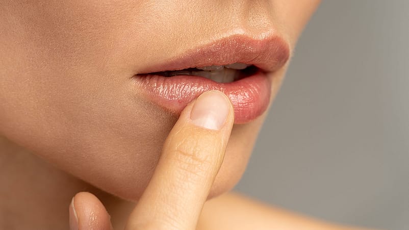 Junge Frau legt ihren Finger an die Lippen