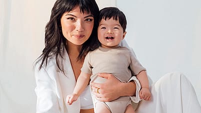 A loving mother holds her smiling baby in a bright, natural setting, showcasing warmth and family bonding—perfect for parenting, wellness, and baby care content.
