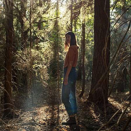 Une femme se tient dans une forêt de pins