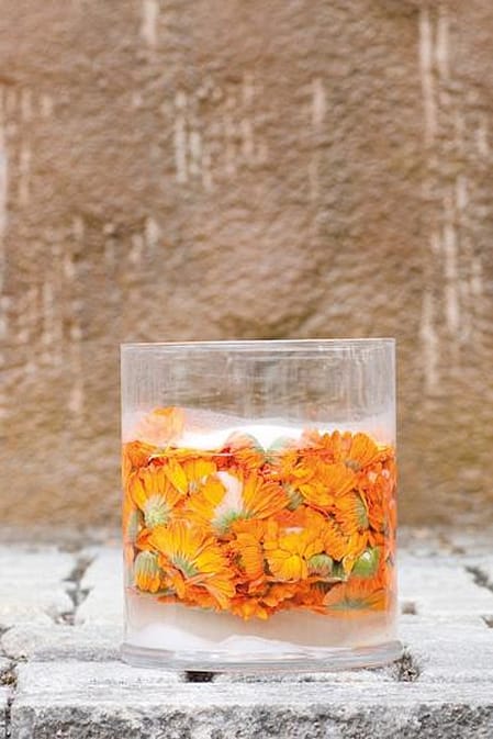 Three glass beakers with calendula flowers.