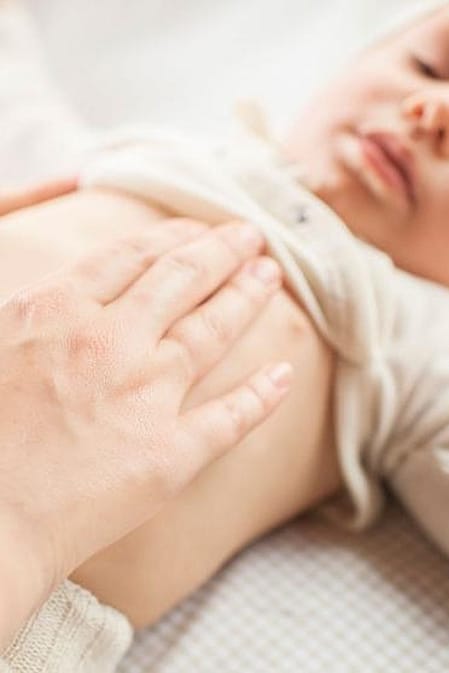 Baby lying down with parents hands on belly