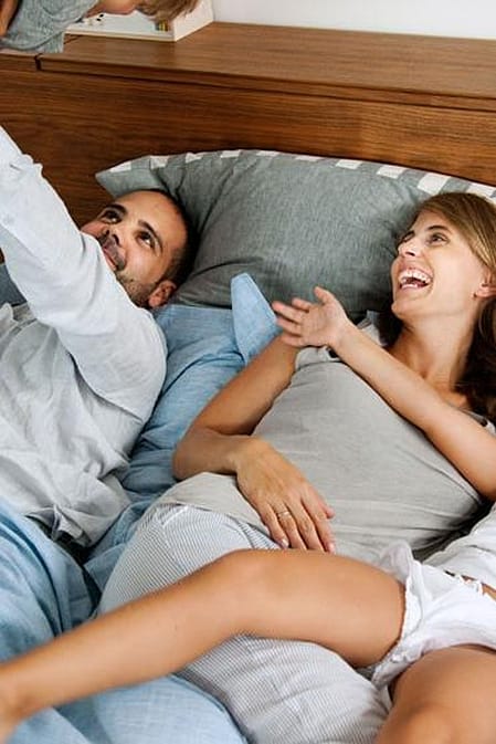 Madre junto a sus hijos durmiendo en una cama