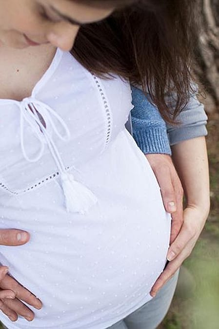 Hände auf dem Bauch einer schwangeren Frau