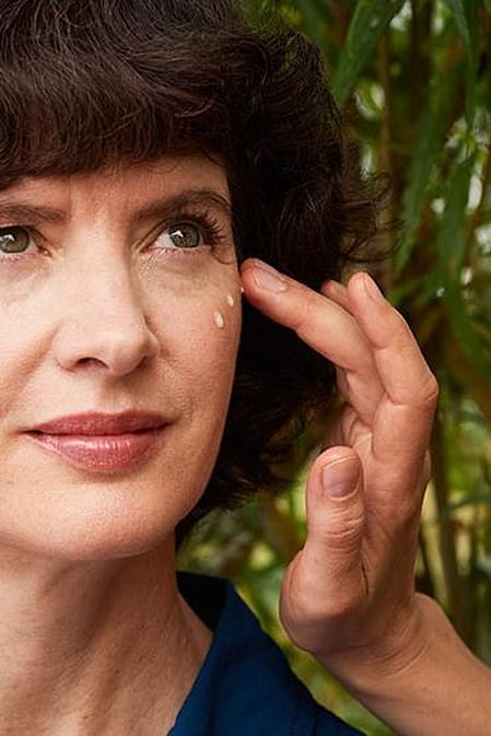 Woman applying eye cream to another woman.
