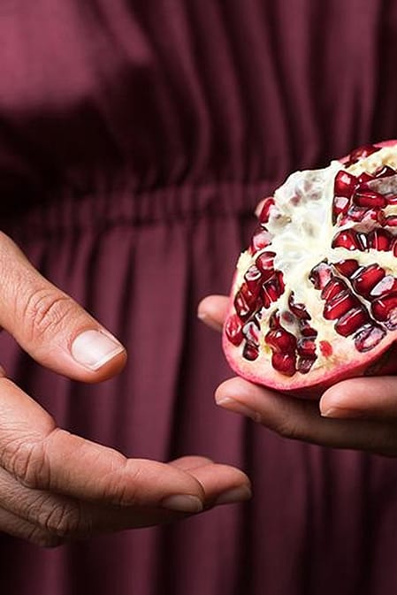 woman holding pomegranate in hand