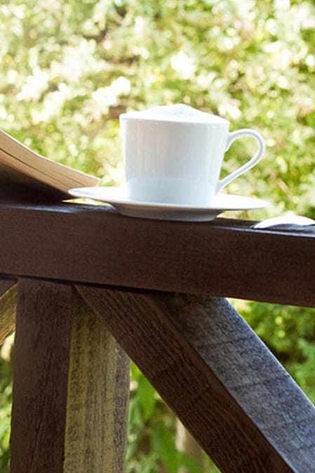 Book, cup of tea at a window showing nature outside