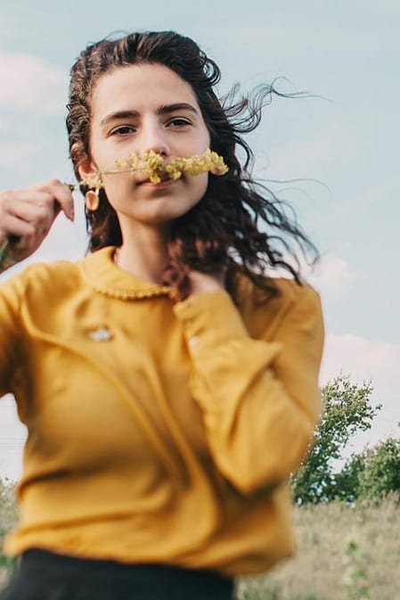 Mujer joven oliendo una flor