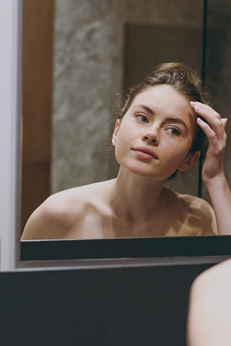 žena si prohlíží akné v zrcadle