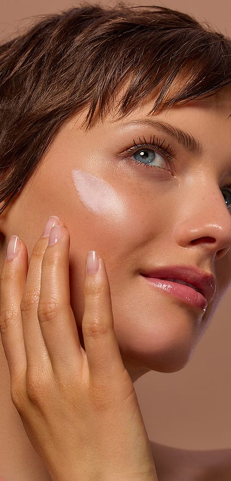 Viso modella che mette crema sulla guancia