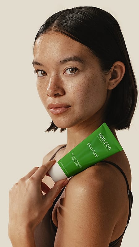 Woman's face next to green leafs.