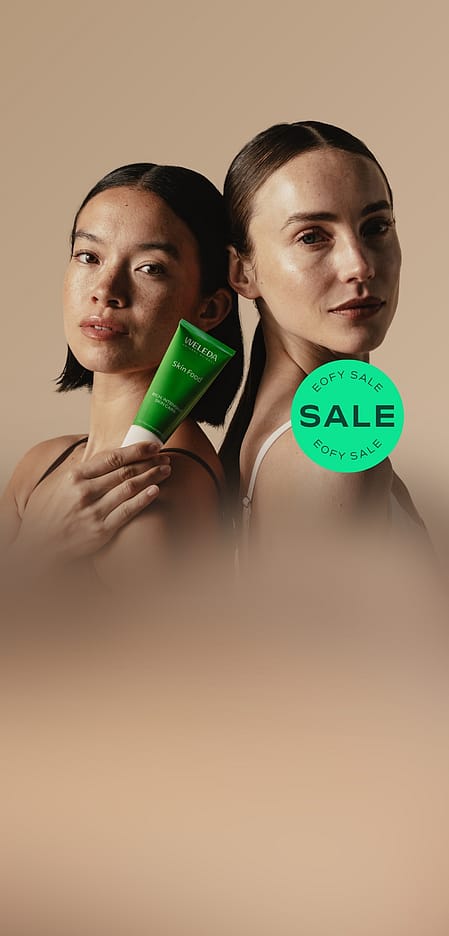 Two women back to back and one holding Weleda Skin Food Original