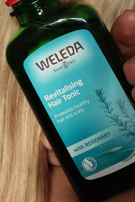 woman holding hair tonic in hand with hair