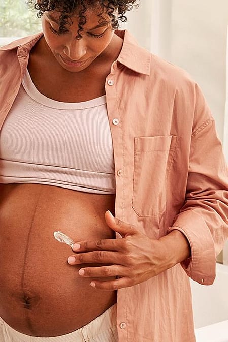 Pregnant woman applying Stretch mark cream to her belly