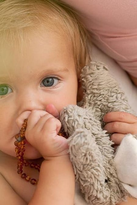 Baby holding a teething necklace and bunny