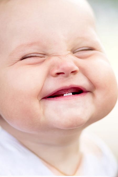 Baby with two bottom teeth grinning