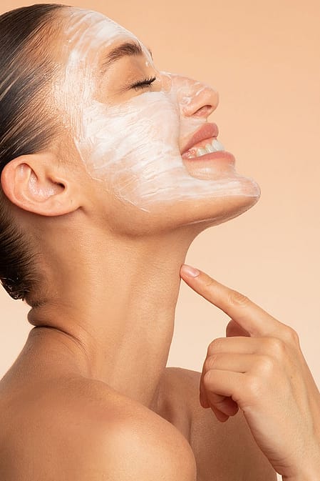 smiling woman applying creme on her face