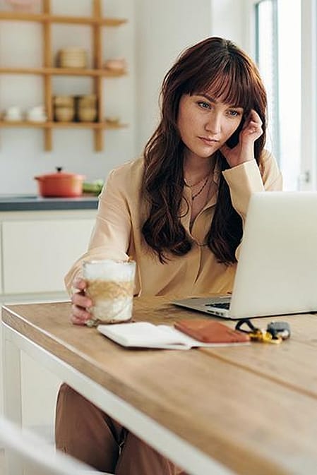 Frau trinkt Kaffee am Computer
