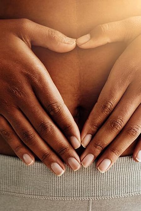 Frau legt ihre Haende auf den Bauch