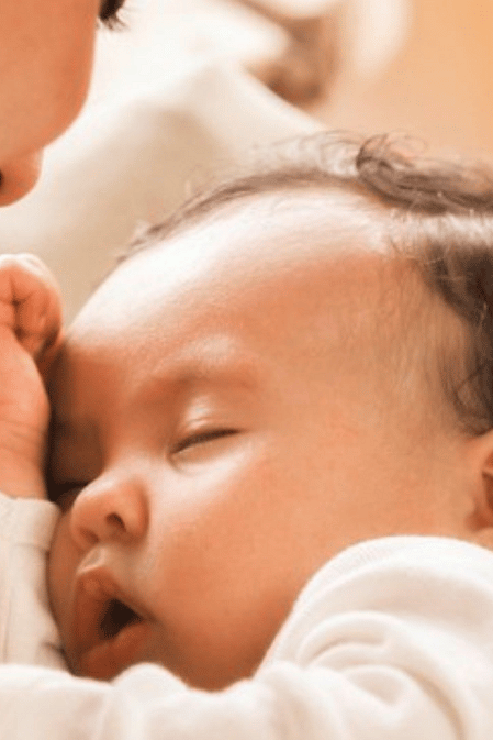 mujer sosteniendo a un bebé dormido en los brazos