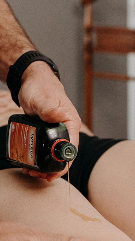 sportive se faisant masser par un kiné avec huile de massage arnica
