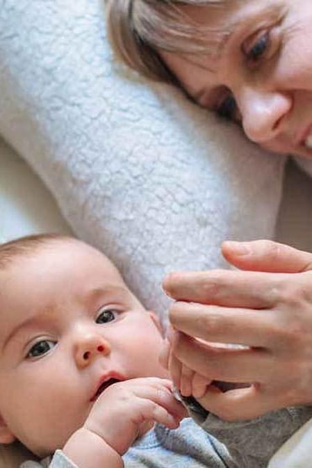 bebe tumbado en la cama con sus padres