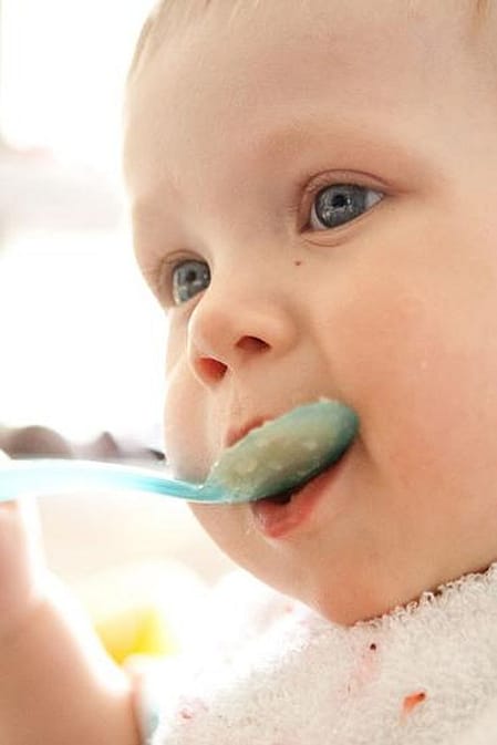 Bebé comiendo con una cuchara en la mano