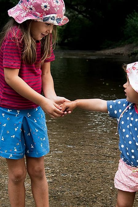 Dos niñas de la mano jugando en el agua