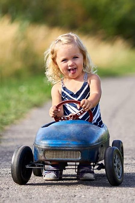 niña montada en un cochecito de juguete