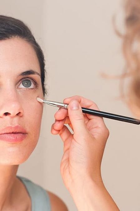 Kvinna framför spegel som sminkar sig