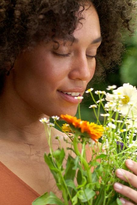Frau in der Natur riecht an Blumen