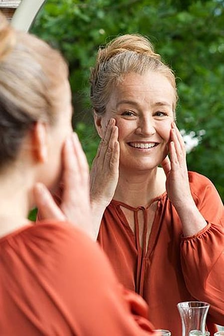 Lächelnde Frau vor dem Spiegel