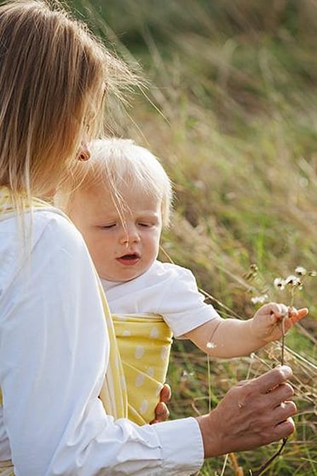 Woman carrying baby outside.