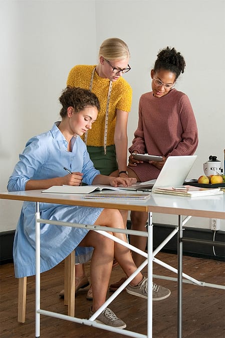Drei Frauen im Buero am Schreibtisch vor dem Laptop